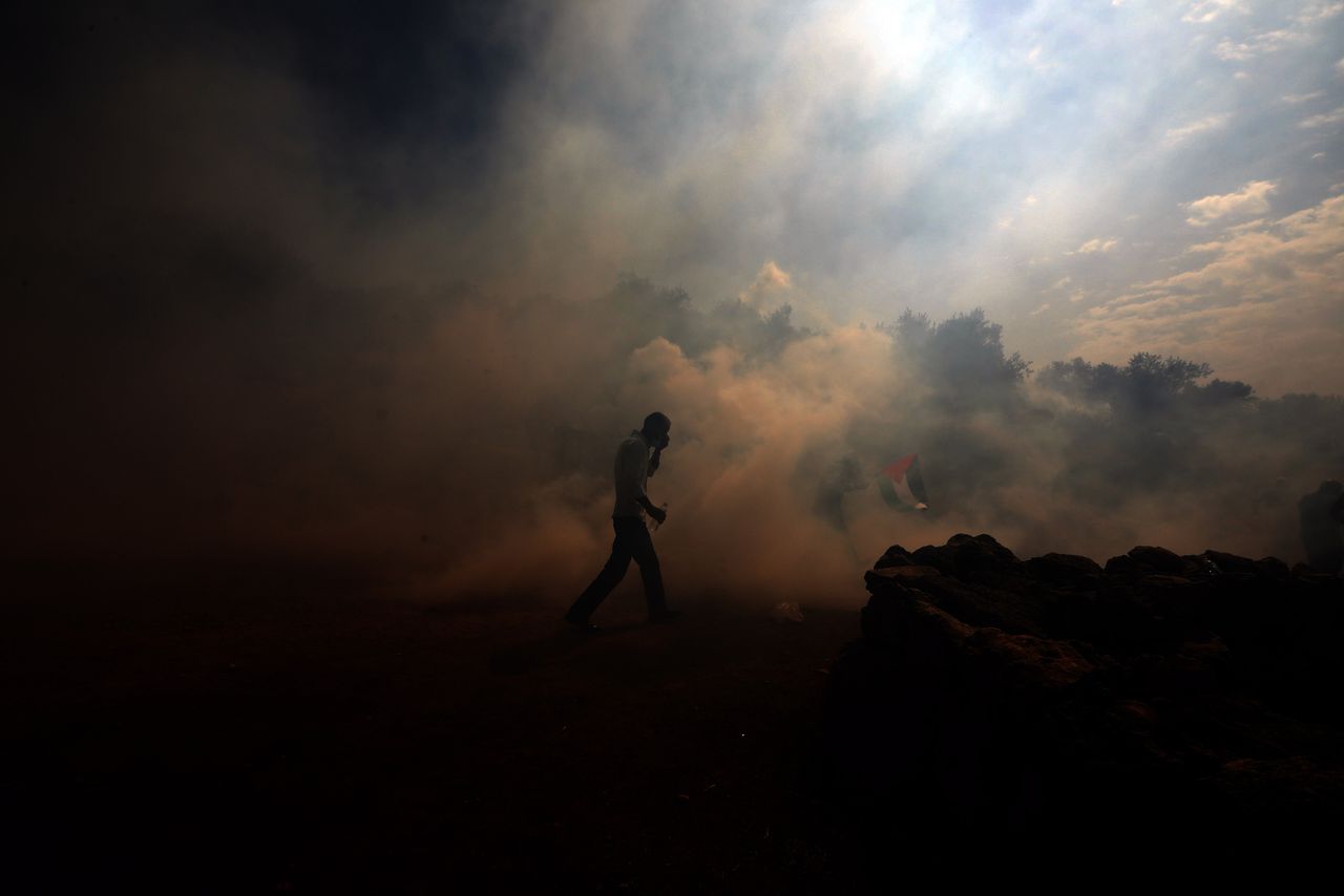 Een Palestijn loopt weg terwijl Israelische soldaten traangas gebruiken om een demonstratie op te breken tegen een illegale nederzetting nabij Nablus op 9 oktober. Er vielen 35 Palestijnse gewonden. Foto: Alaa Badarneh/EPA