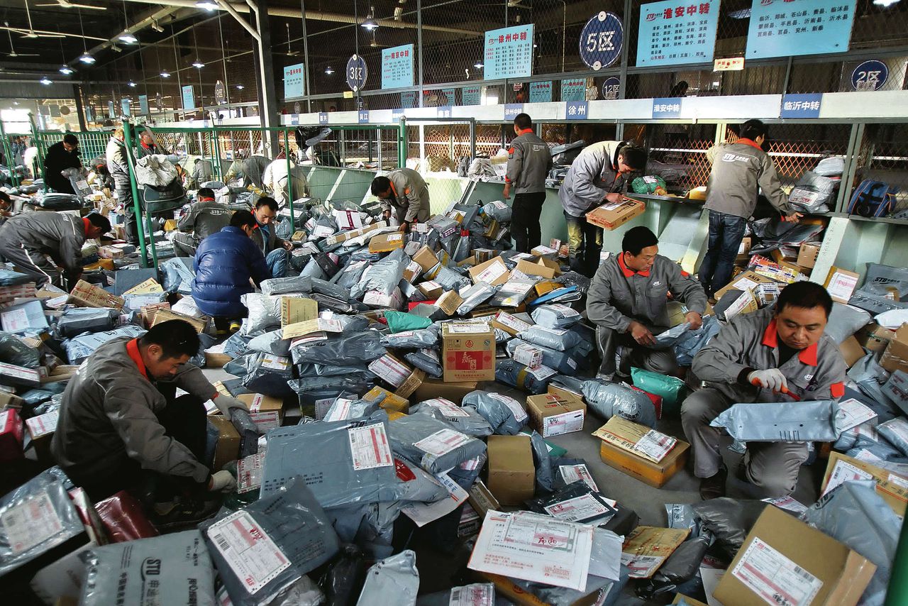 Werknemers sorteren pakketjes voor een vervoersbedrijf in het oosten van China. De overheid moedigt groei van de internethandel op het Chinese platteland aan. Foto Reuters