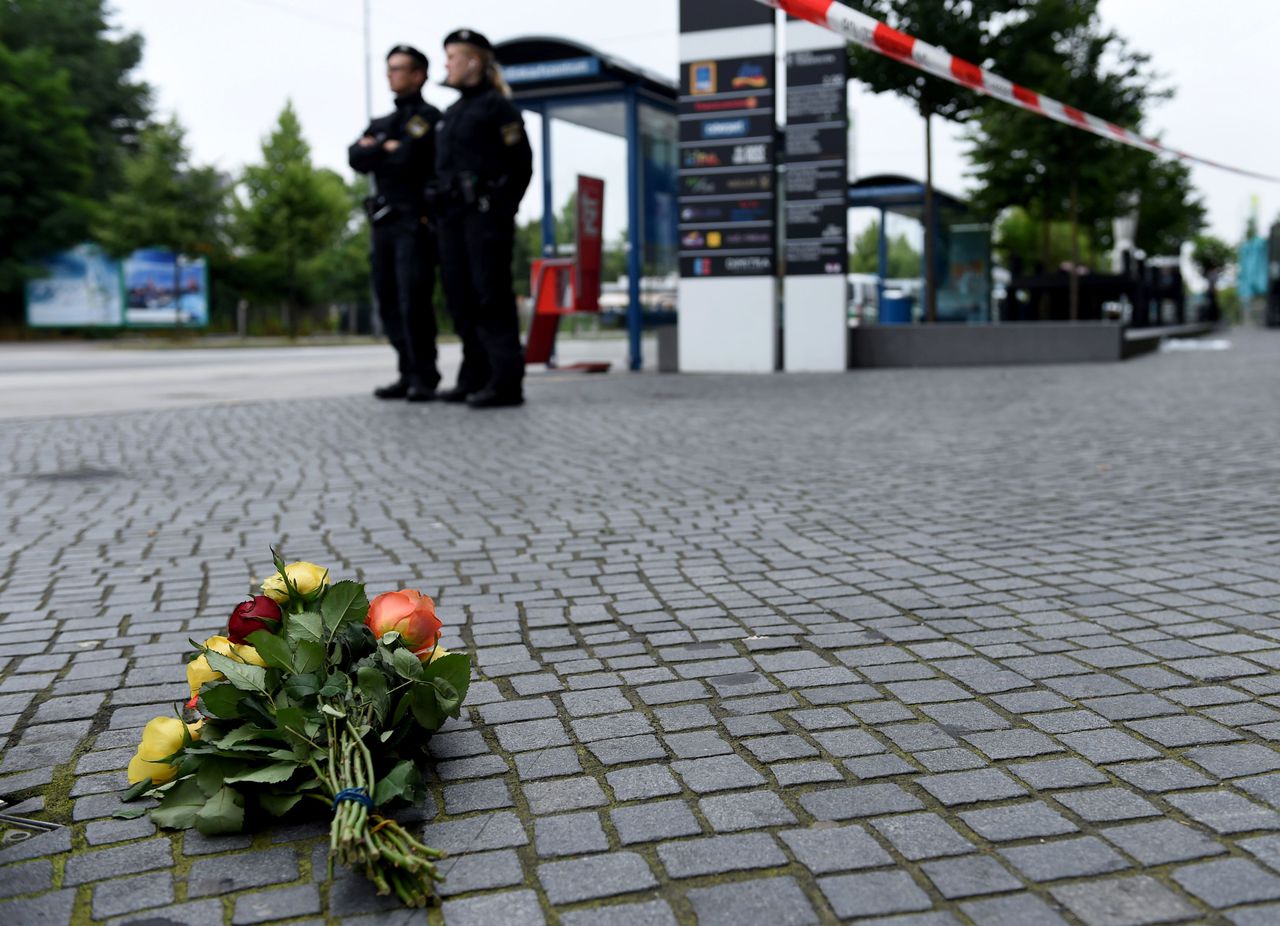Politieagenten staan bij bloemen die zijn neergelegd ter nagedachtenis aan de slachtoffers in München.