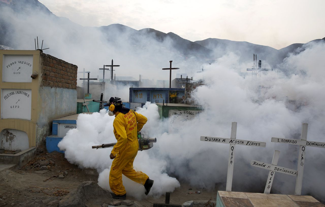 Een gezondheidsmedewerker voert preventief reinigingswerkzaamheden uit tegen het zikavirus op een begraafplaats in Lima.