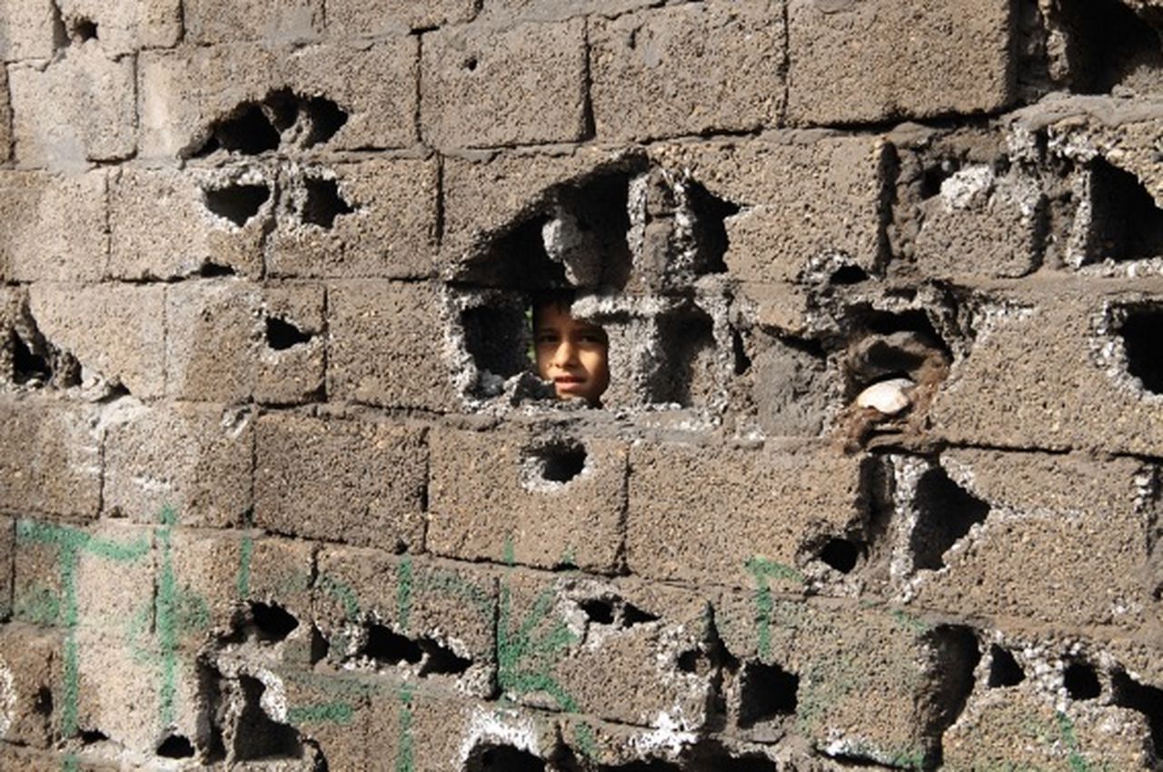 Een jongetje kijkt door een gat in een muur in Sirnak, een dorpje niet ver van de Turkse stad Cizre
