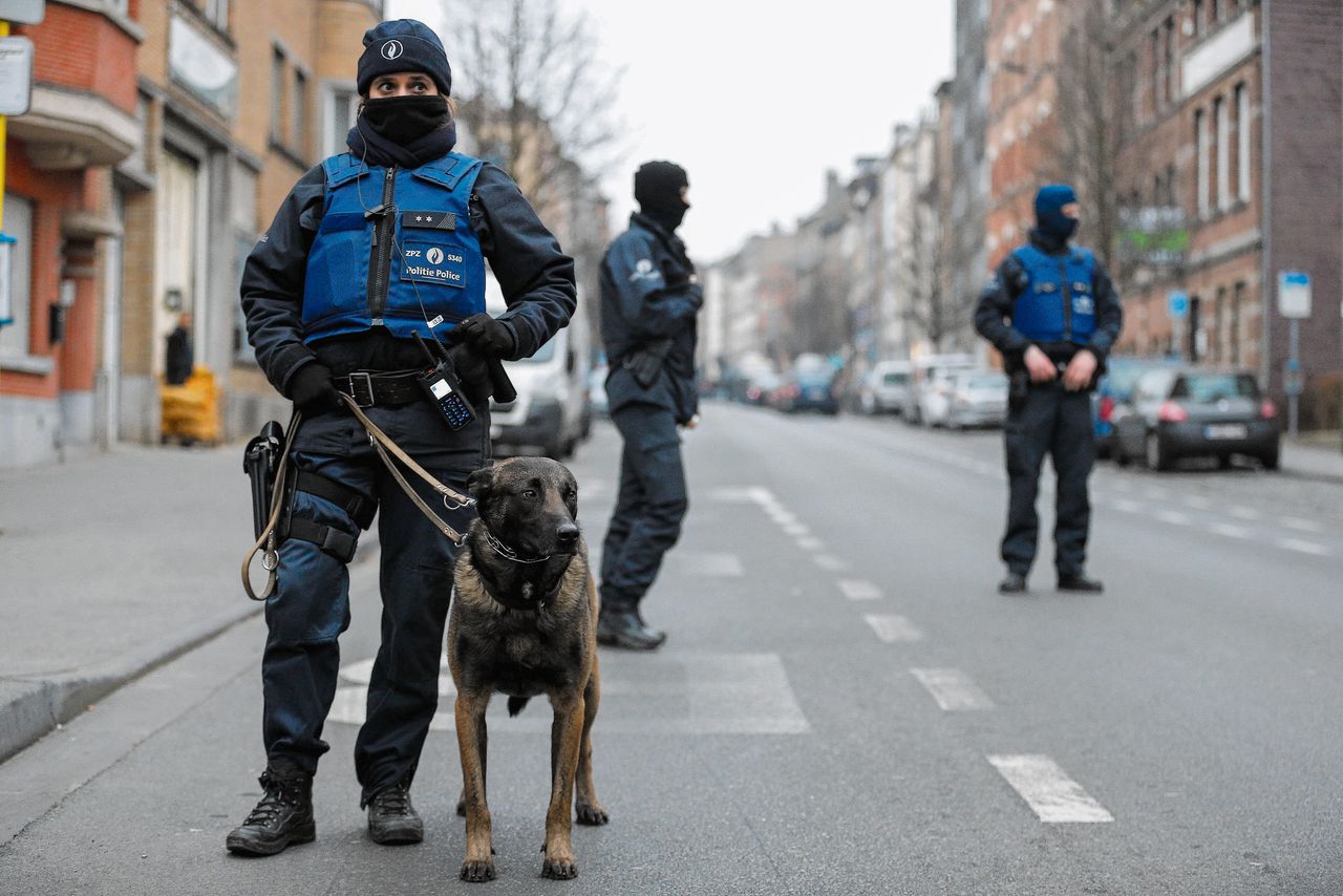Een straat in Molenbeek wordt bewaakt door politie terwijl de buurt wordt uitgekamd in een zoektocht naar de verdachten.