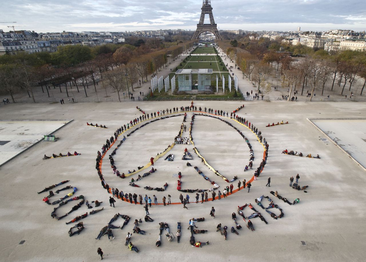 Demonstranten vormen een vredesteken tijdens de klimaattop in Parijs in december. Vrijdag is het daar bereikte akkoord ondertekend.