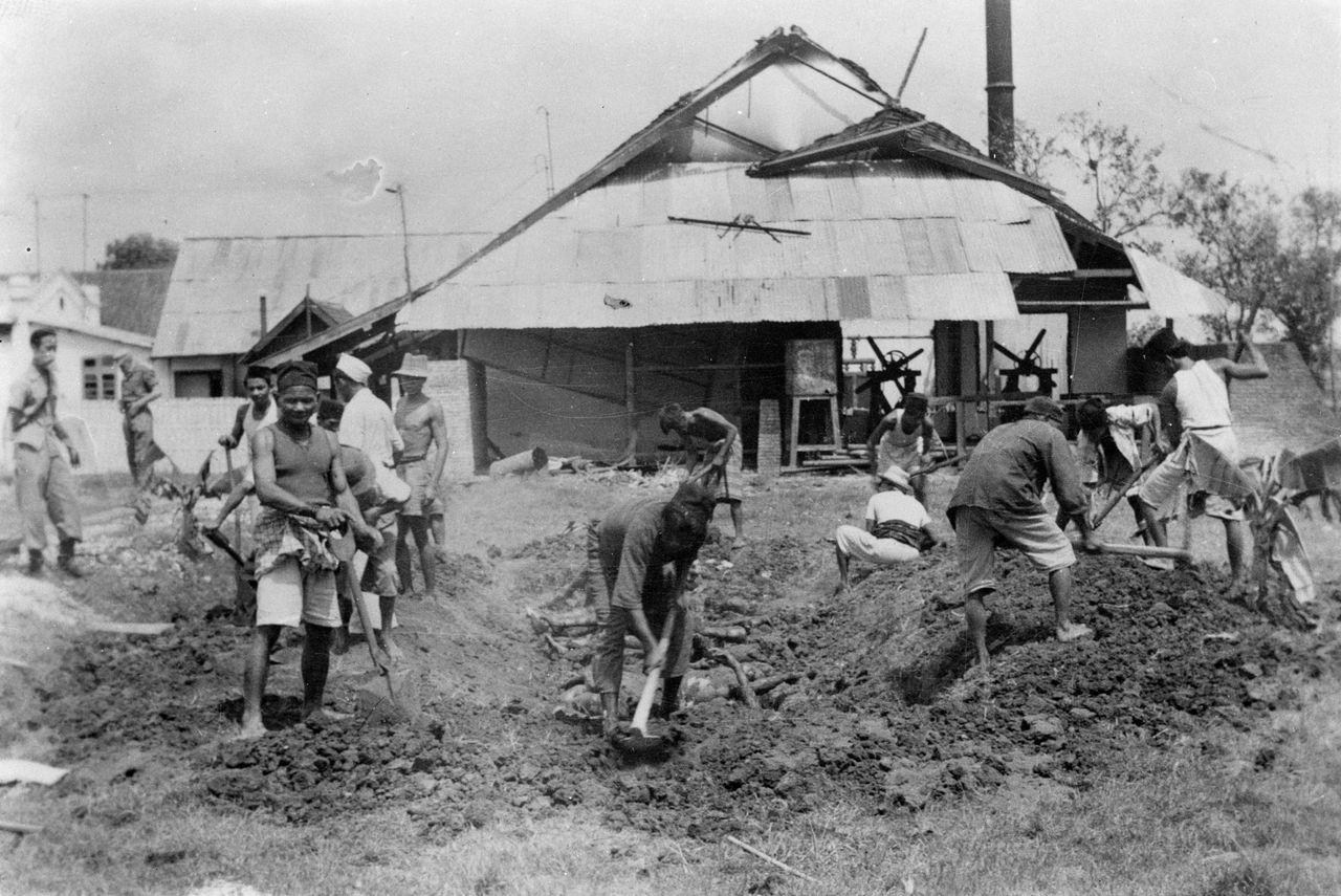 Lichamen van vermoorde Chinezen worden in juli 1947 in een massagraf begraven bij een conservenfabriek in de buurt van Malang, Java.