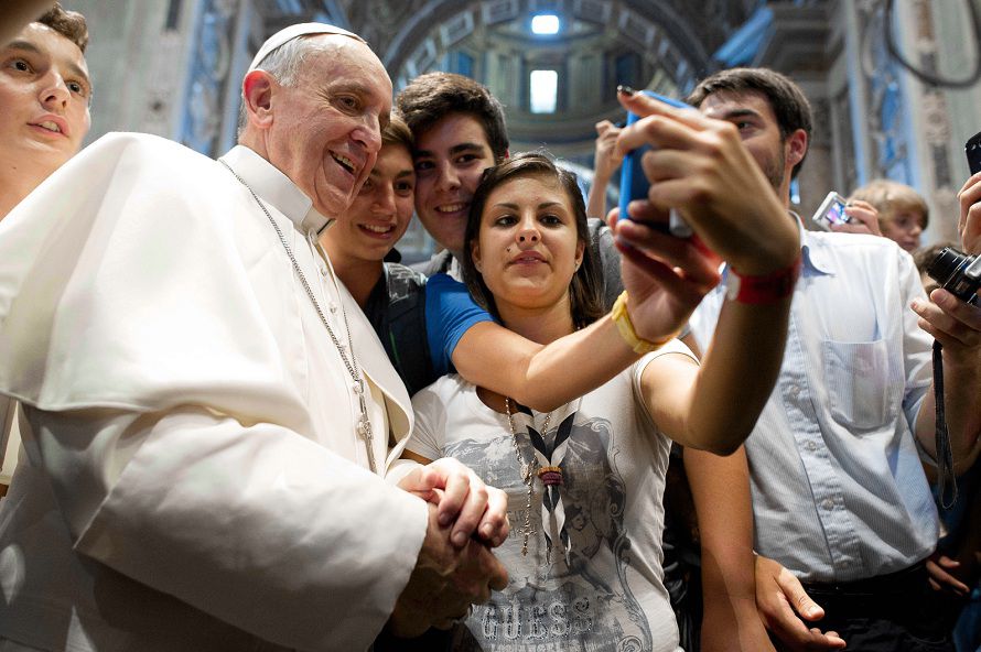 De paus poseert in de Sint-Pietersbasiliek met een aantal jongeren voor een selfie .