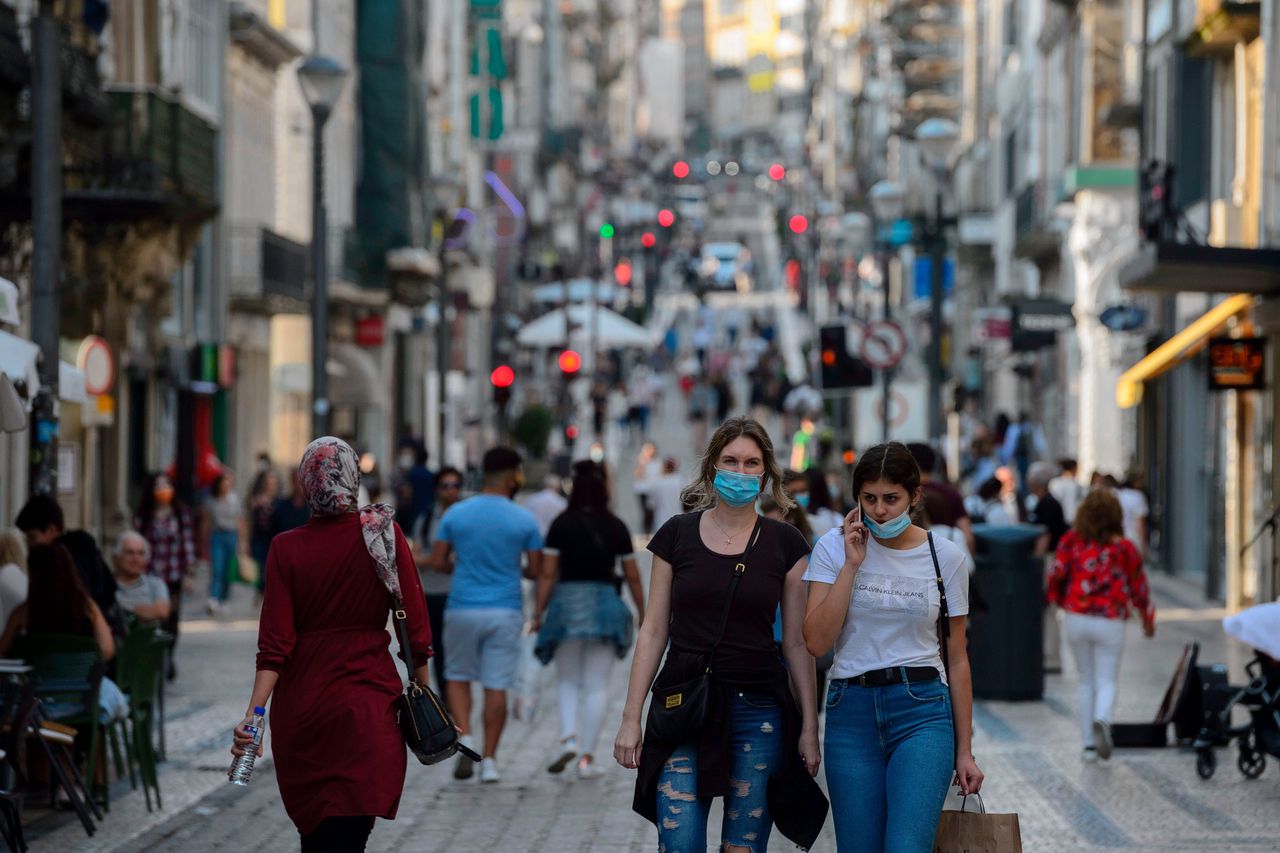 Mensen wandelen over de Santa Catarinastraat in Porto, begin juni. Hier zijn de winkelcentra nog open, in Lissabon moeten ze in een aantal stadsdelen weer dicht omdat er relatief veel besmettingen zijn.