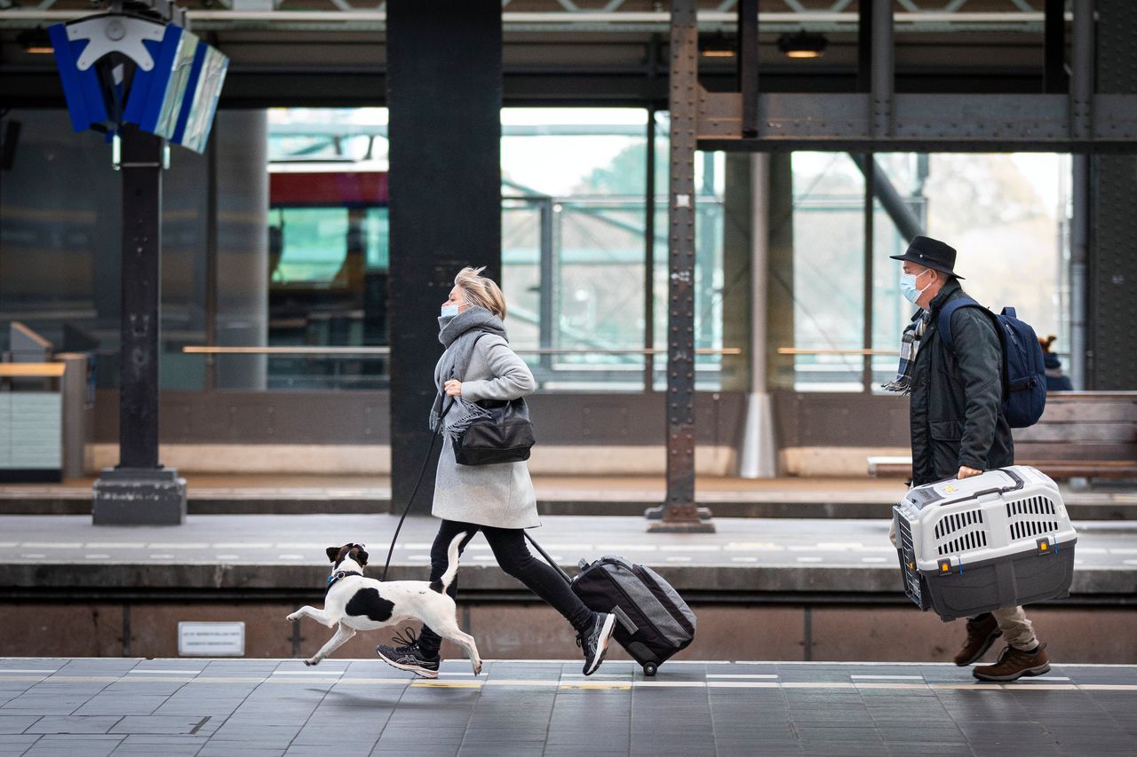 Reizigers met mondkapjes rennen om de trein te halen op station Amsterdam Centraal.