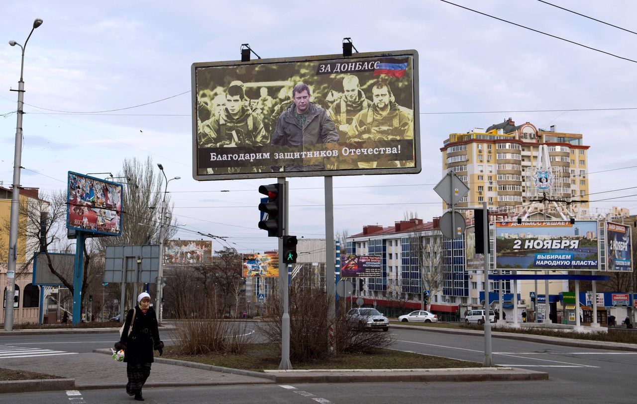 Een vrouw loopt onder een billboard door van separatistleider Aleksandr Zachartsjenko in Donetsk.