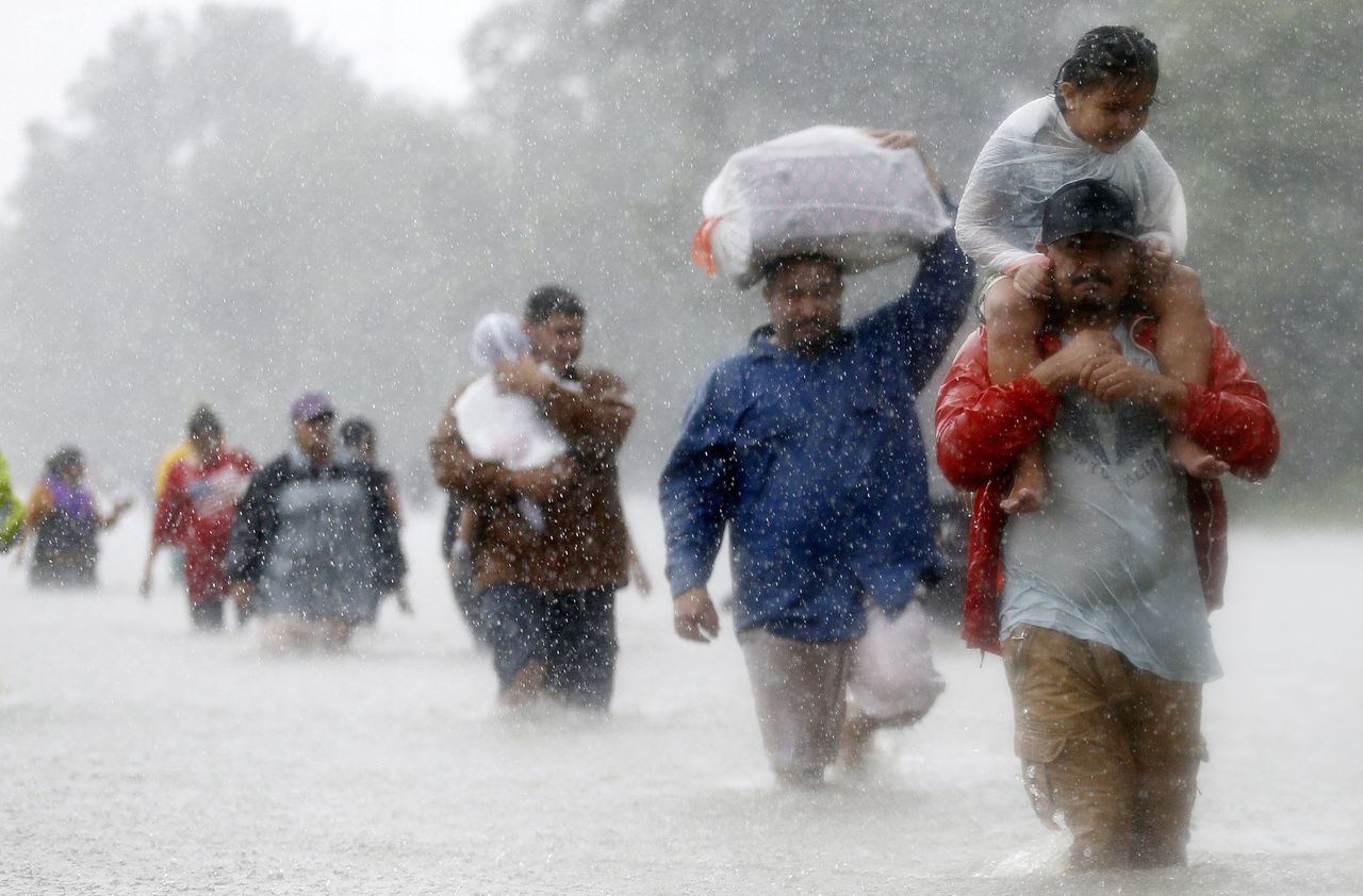Bewoners van de Amerikaanse stad Houston lopen door ondergelopen straten als gevolg van de tropische storm Harvey. Met de opwarming van het klimaat neemt het aantal orkanen en stormen toe.