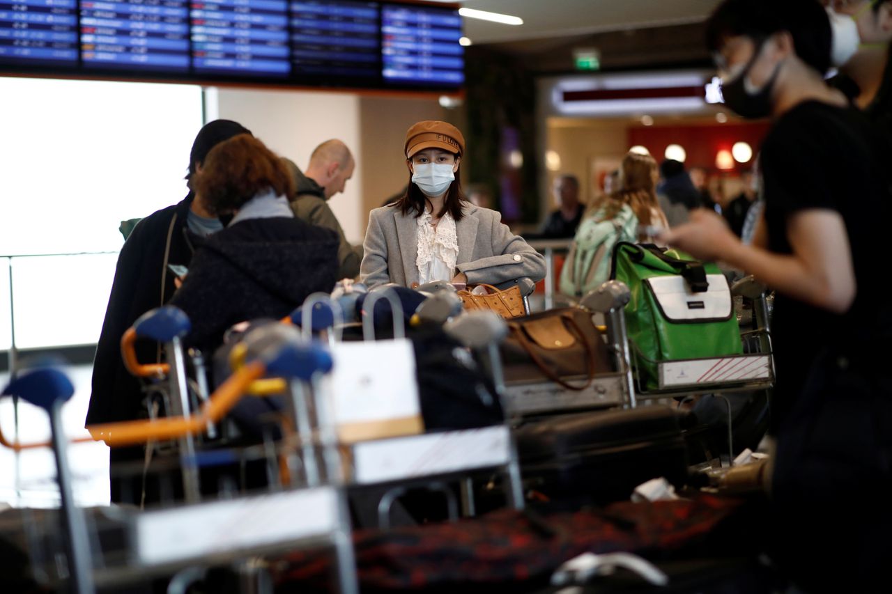 Toeristen uit Beijing dragen mondkapjes bij aankomst op luchthaven Charles de Gaulle in Parijs.