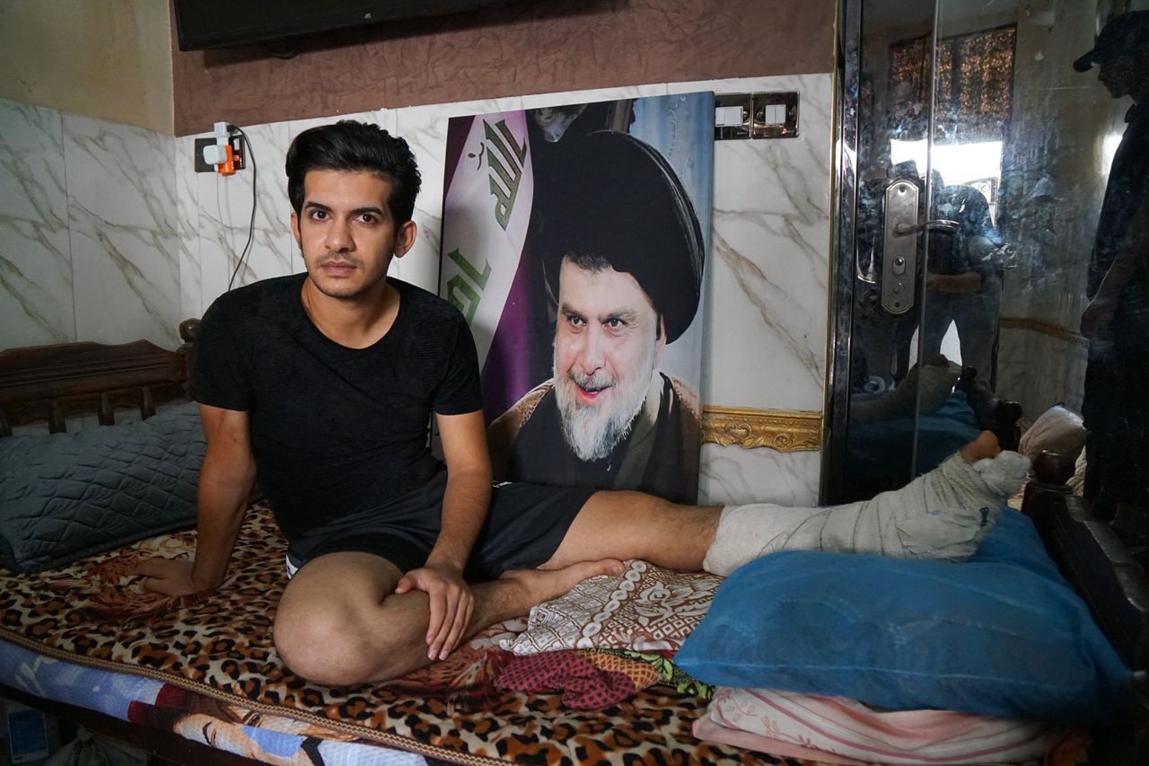 Hussein Salim Mohammed ligt op bed met een portret van Moqtada al-Sadr. Hij raakte eind augustus gewond toen hij samen met andere aanhangers van Sadr de Groene Zone in Bagdad bestormde.