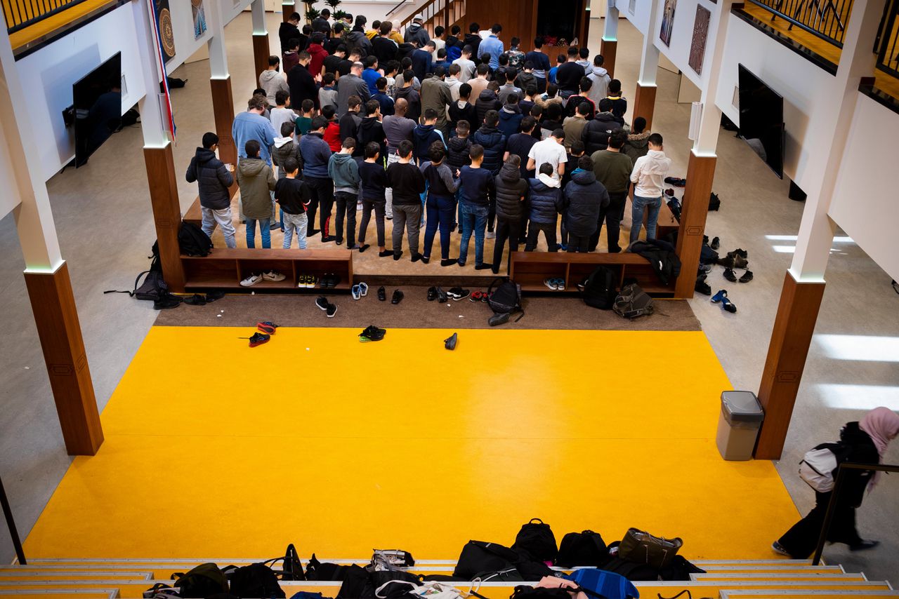 Jongens en mannelijke docenten bidden op het Cornelius Haga Lyceum in Amsterdam, december 2019.