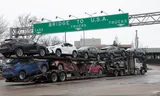 Een transportwagen met nieuwe auto’s rijdt richting de Ambassador Bridge van Windsor naar de Amerikaanse staat Michigan. Foto Rebecca Cook/Reuters 