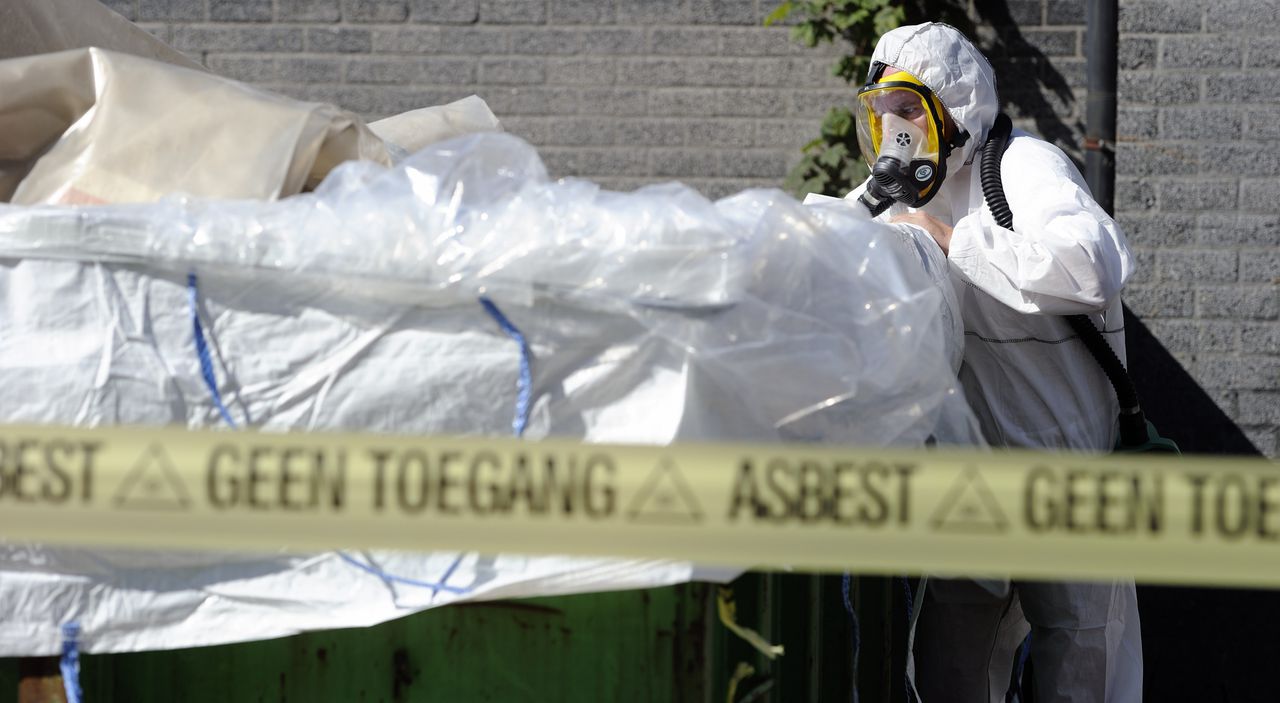 Een medewerker van een asbestsaneringsbedrijf verwijdert asbest.