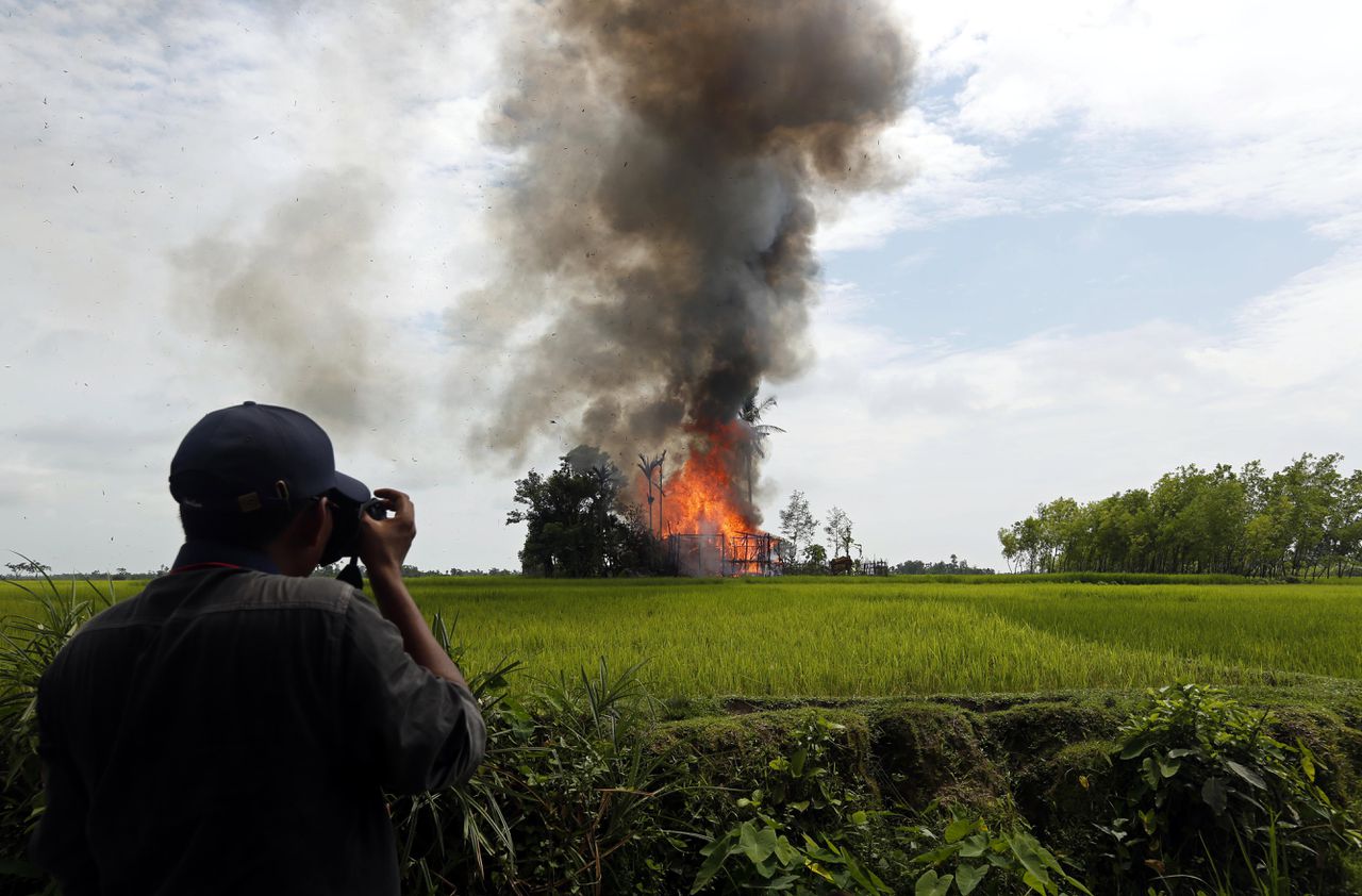 Een journalist fotografeert een brandende hut in de deelstaat Rakhine.