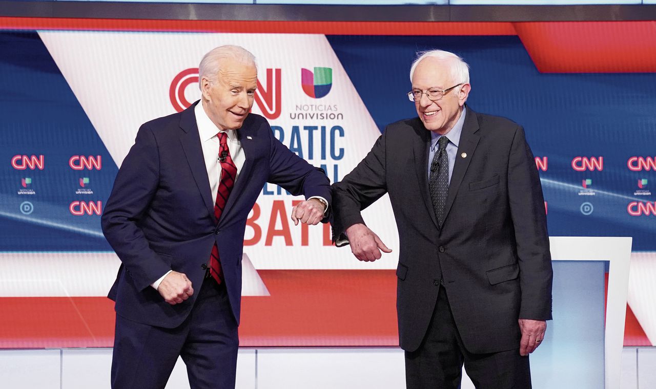 De Democratische presidentskandidaten Joe Biden (links) en Bernie Sanders begroeten elkaar voor hun debat.