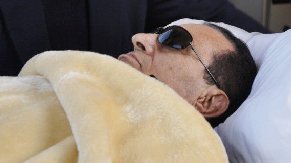 Mubarak, op beeld tegen het proces tegen hem, dat hij goeddeels vanaf een bed volgde.