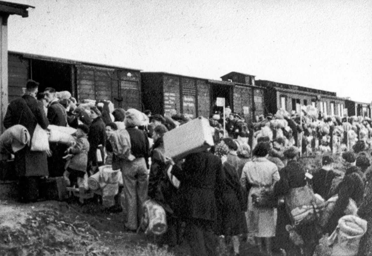 Joden staan te wachten bij de goederenwagons van een trein in doorvoerkamp Westerbork.