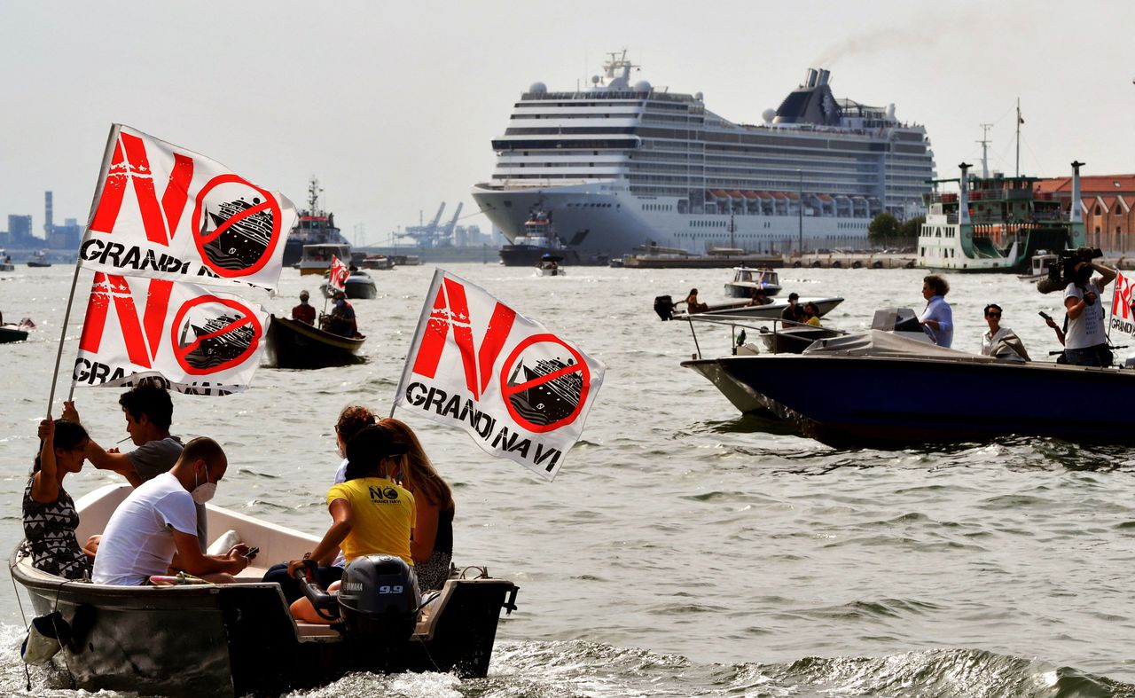 Demonstranten voeren in eigen bootjes mee met de MSC Orchestra, om hun onvrede te uiten tegen de cruiseschepen in Venetië. De industrie heeft een jaar stilgelegen.