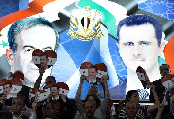 Syriërs houden foto's van Assad vast in de vorm van een hartje, tijdens een bijeenkomst voor de aankomende presidentsverkiezingen . De campagne hiervoor startte deze week.