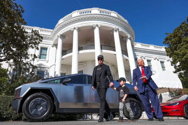 Donald Trump prijst staande voor het Witte Huis ten overstaan van de media de Tesla, in gezelschap van ceo Elon Musk en diens zoontje genaamd ‘X Æ A-12’, maart 2025.