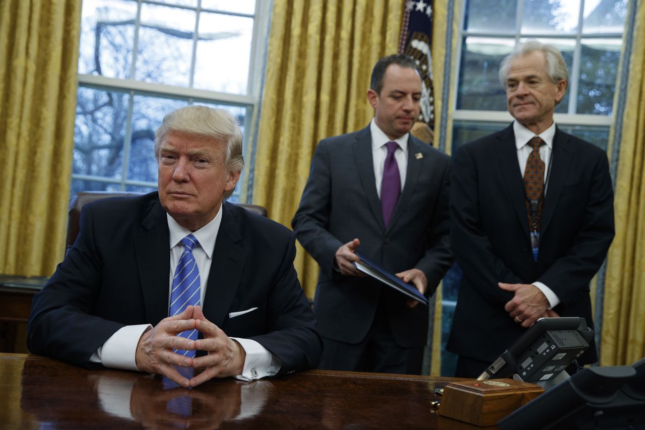 Peter Navarro (rechts) en stafchef Reince Priebus vergezellen president Trump bij het tekenen van drie decreten.