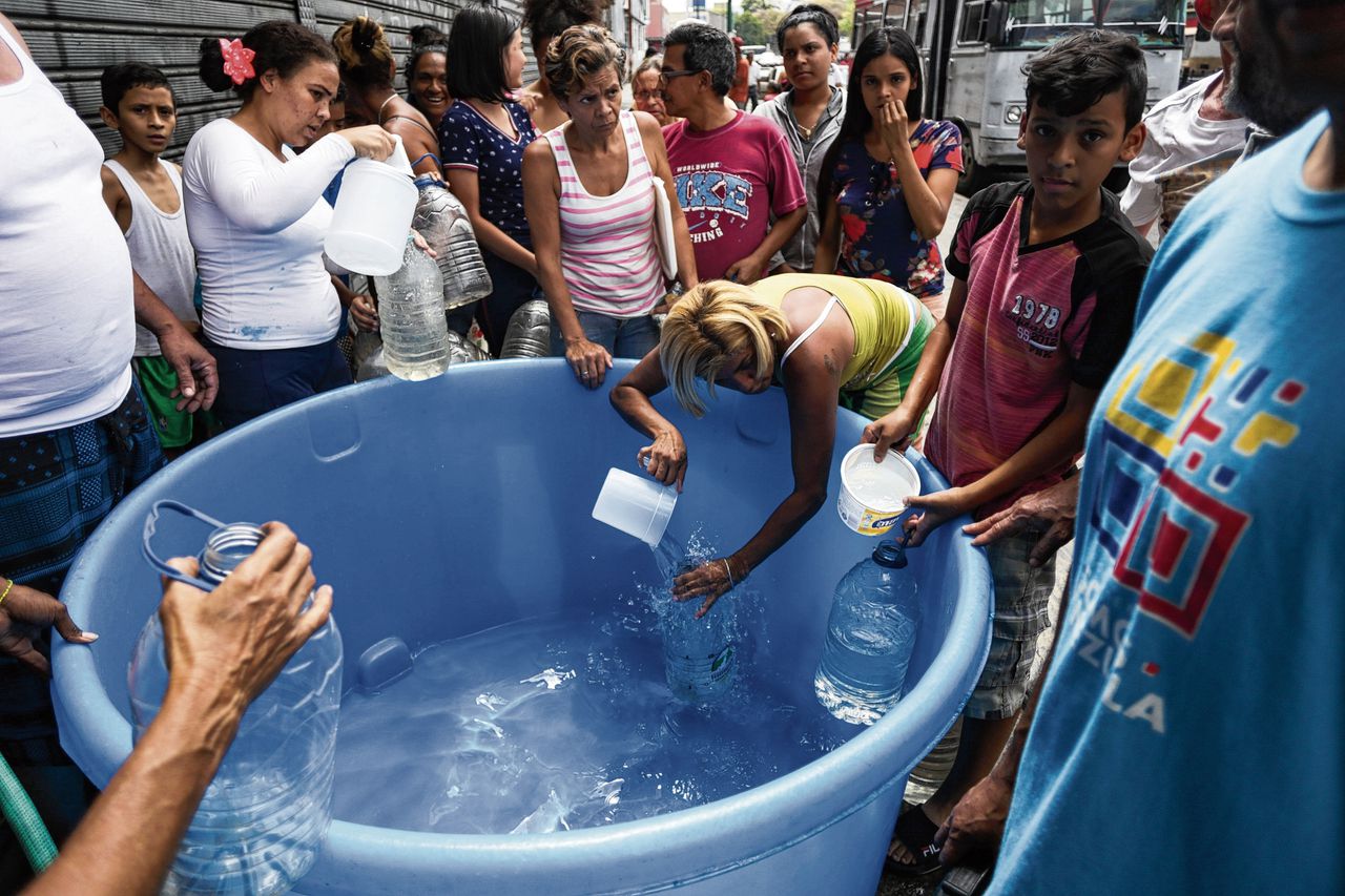 Inwoners van Caracas vullen flessen water. Door de stroomstoring is er geen stromend water.