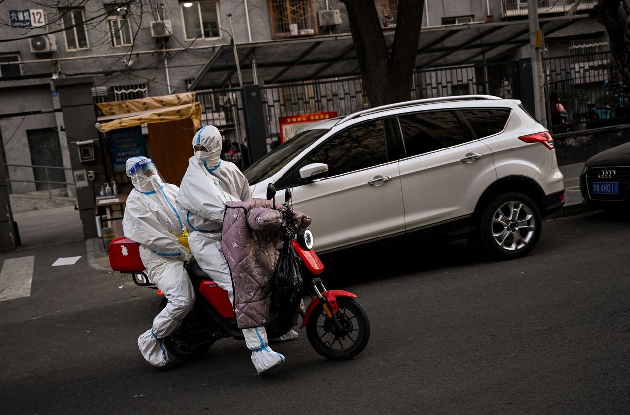 Chinese zorgmedewerkers rijden door een wijk in Beijing die in lockdown is.