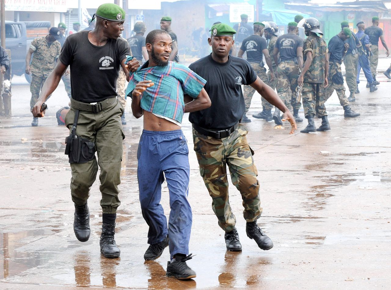 Een demonstrant wordt weggevoerd door politieagenten bij een oppositiebijeenkomst in een stadion in Conakry in 2009. Guinese militairen doden daar ten minste 157 mensen.