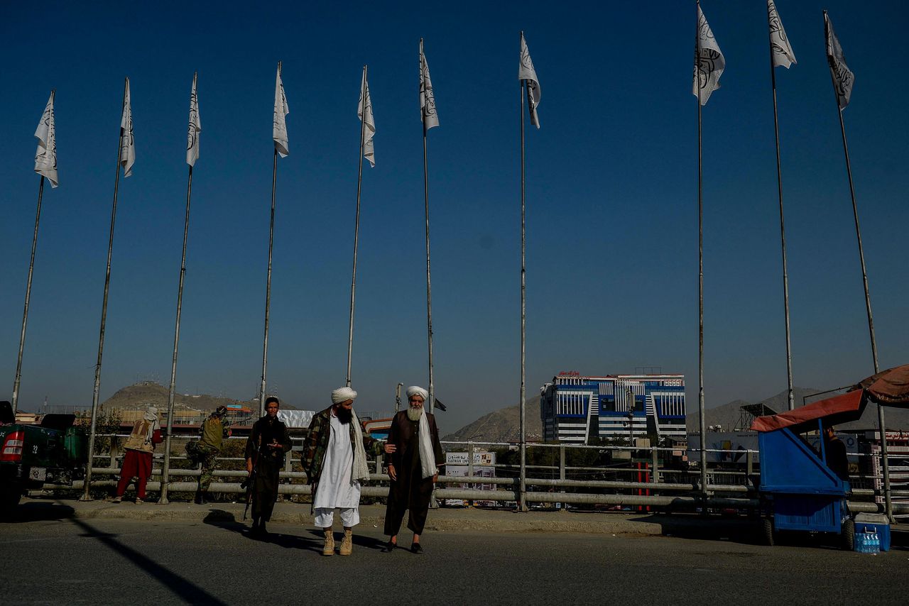 Talibanstrijders bij vlaggen in Kabul.