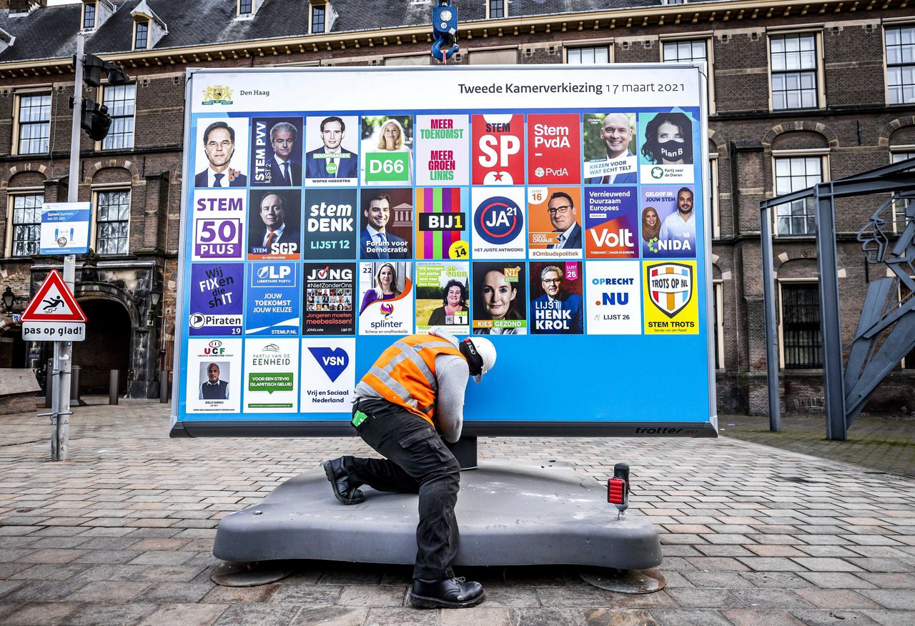 Medewerkers plaatsen een verkiezingsbord voor de Tweede Kamerverkiezingen op het Buitenhof.
