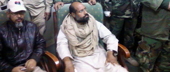 Caption: A mobile phone picture taken by one of his guards shows Saif al-Islam Gaddafi sitting with his captors in Obari airport November 19, 2011. Saif al-Islam has been captured in Libya's southern desert, scared and with only a handful of supporters, by fighters who vow to hold him in the mountain town of Zintan until there is a government to hand him over to. Picture taken November 19, 2011. REUTERS/Handout (LIBYA - Tags: POLITICS CIVIL UNREST) FOR EDITORIAL USE ONLY. NOT FOR SALE FOR MARKETING OR ADVERTISING CAMPAIGNS. THIS IMAGE HAS BEEN SUPPLIED BY A THIRD PARTY. IT IS DISTRIBUTED, EXACTLY AS RECEIVED BY REUTERS, AS A SERVICE TO CLIENTS