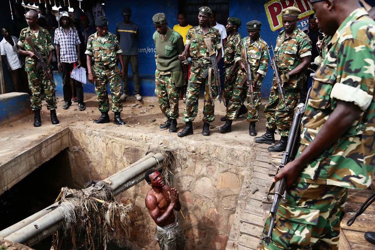Een lid van de jeugdmilitie van de regeringspartij vraagt soldaten om bescherming tegen een groep demonstranten, nadat hij vluchtte via een riool in de wijk Cibitoke in Bujumbura. In Burundi zijn honderden mensen gedood en honderdduizenden op de vlucht sinds de protesten tegen een nieuwe ambtstermijn van president Pierre Nkurunziza.