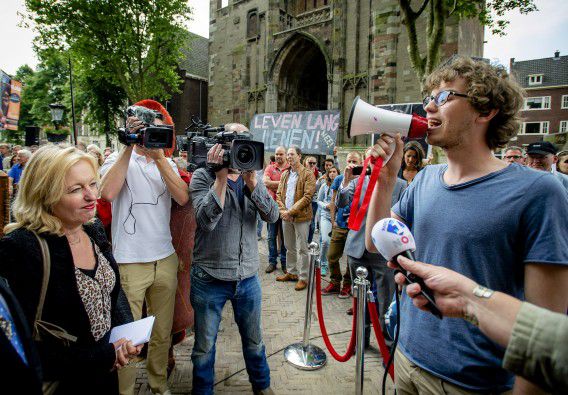 Studenten protesteren tegen het leenstelsel. Verantwoordelijk minister Jet Bussemaker (PvdA, Onderwijs) kijkt toe.