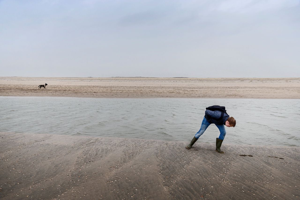 Een fossielenzoeker op de Zandmotor, in de buurt van Kijkduin. Rijkswaterstaat laat veel zand opspuiten langs de kust. Dit komt uit de Noordzee en bevat veel archeologische objecten uit Doggerland.