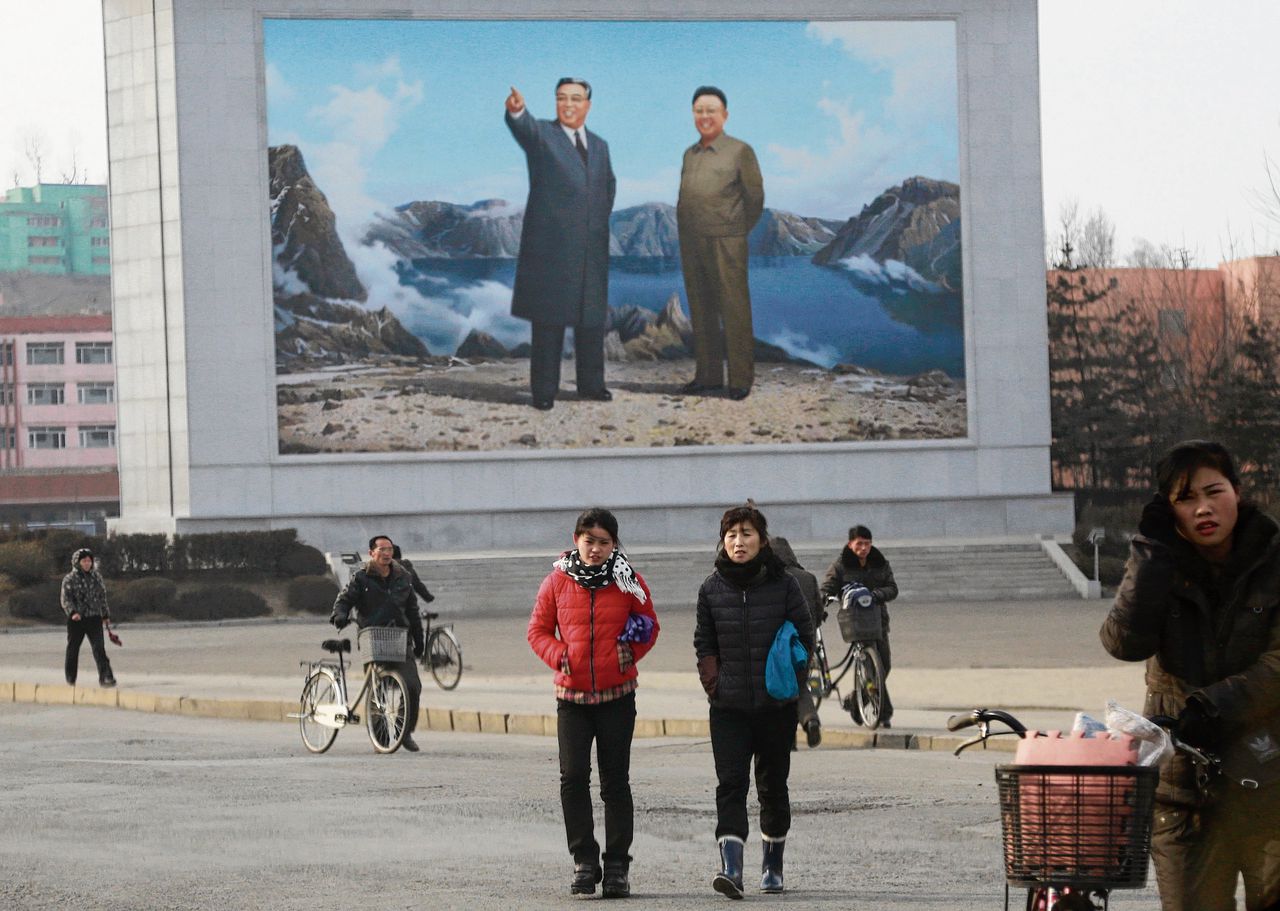 Noord-Koreanen staan voor een schildering van de vroegere leiders Kim Il-sung en Kim Jong-il.