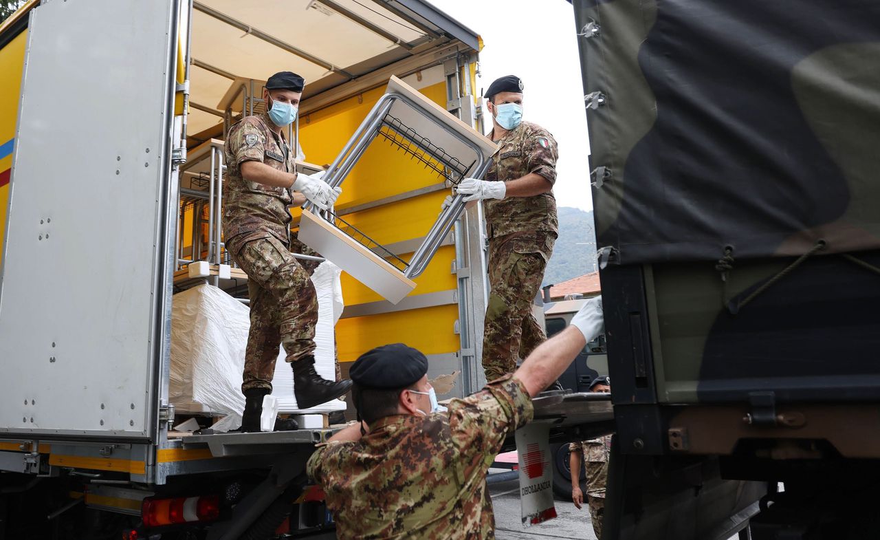 Italiaanse militairen helpen in Bergamo bij de distributie van éénpersoonsschoolbankjes.