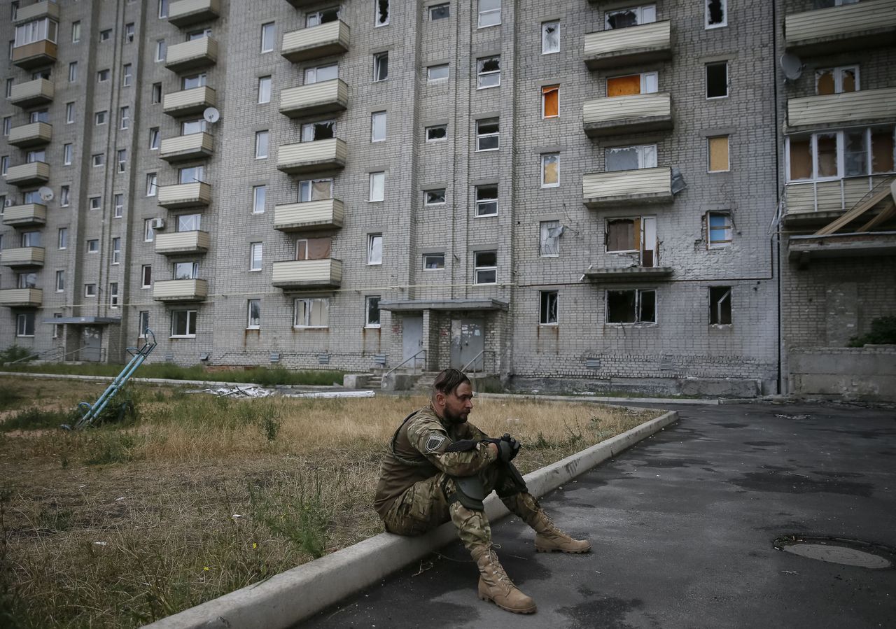 Een Oekraïense soldaat zit op een stoeprand in Avdejevka, nabij Donetsk.