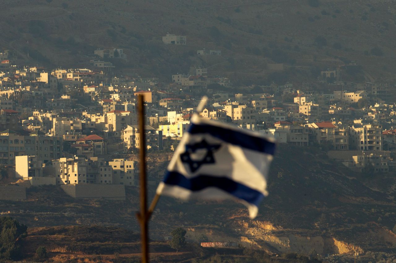 Een Israëlische vlag met op de achtergrond het dorp Majdal Shams in het door Israël bezette gebied van de Golanhoogten.