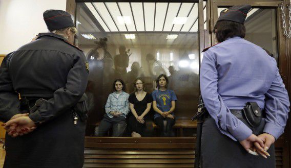 Drie leden van Pussy Riot zitten in een cel in de rechtbank van Moskou, in augustus 2012. De derde vrouw, Jekaterina Samoetsevitsj, werd na haar veroordeling in hoger beroep vrijgelaten.