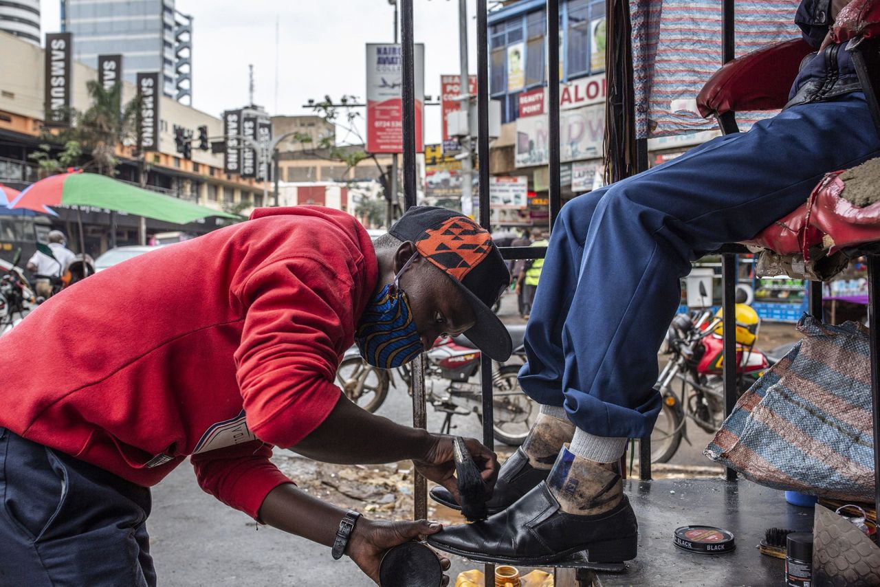 Een schoenenpoetser in Nairobi, vorige week. Een groot deel van de Kenianen werkt in de informele economie, die hard wordt getroffen door het coronavirus.