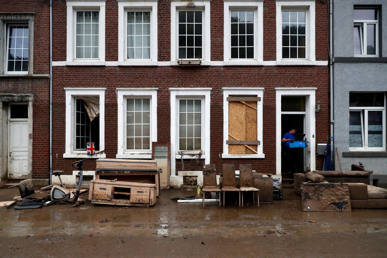 Een man in het Belgische Pepinster ruimt zaterdag puin op voor de deur van zijn woning. Pepinster werd zwaargetroffen door het noodweer vorige week.