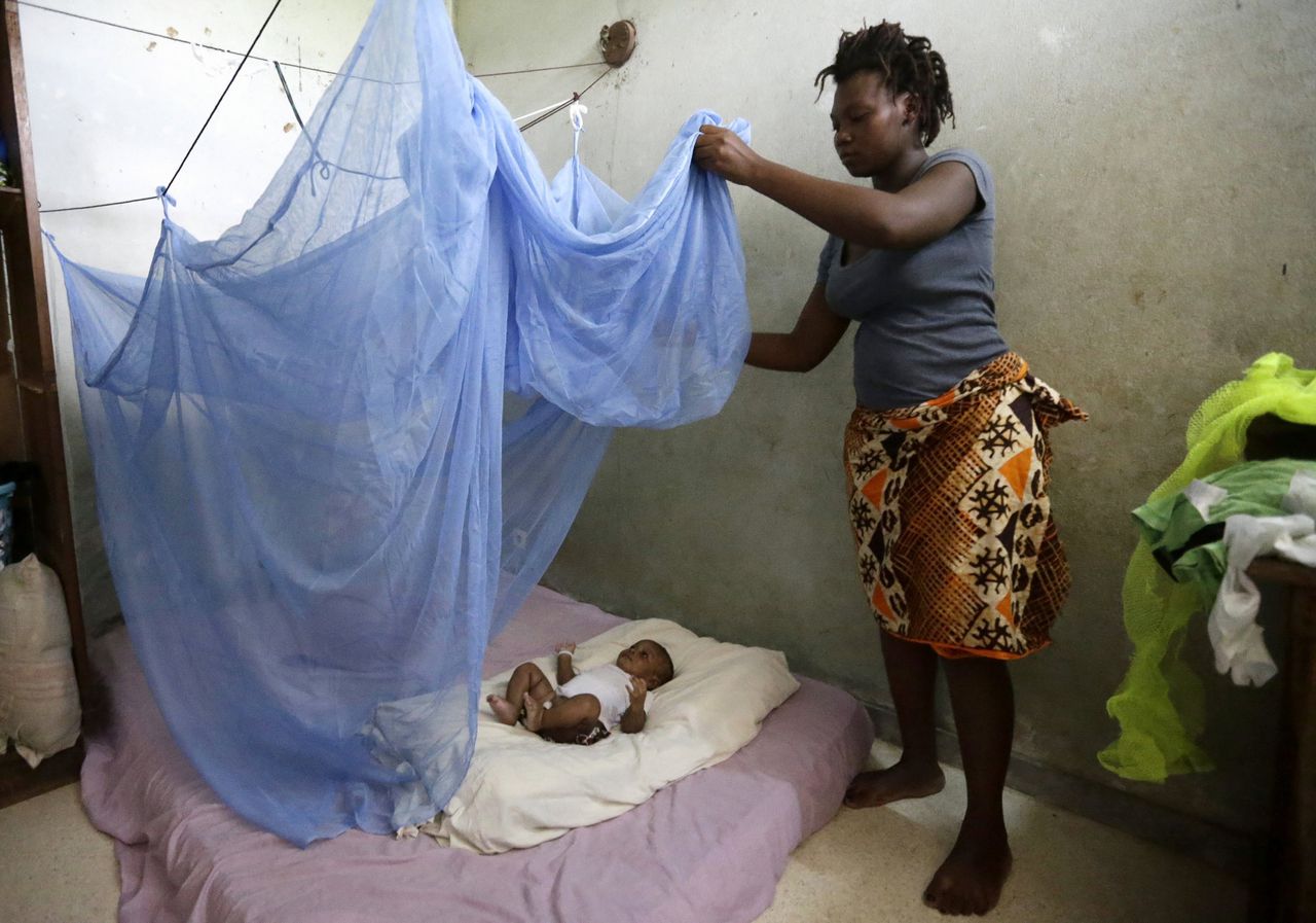 Moeder installeert muskietennet voor haar kind in Ivoorkust.