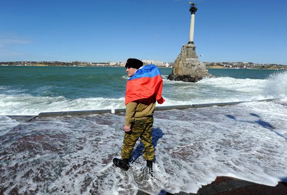 Een pro-Russische zelfverdedigingsactivist loopt met een Russische vlag aan de waterkant in Sebastopol.