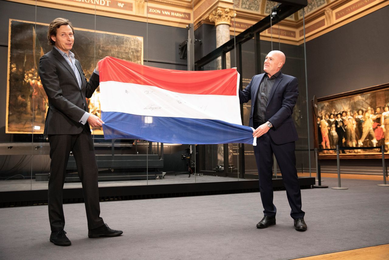André Kuipers (rechts) overhandigt de vlag uit het ISS aan Harm Stevens, conservator van het Rijksmuseum Amsterdam.