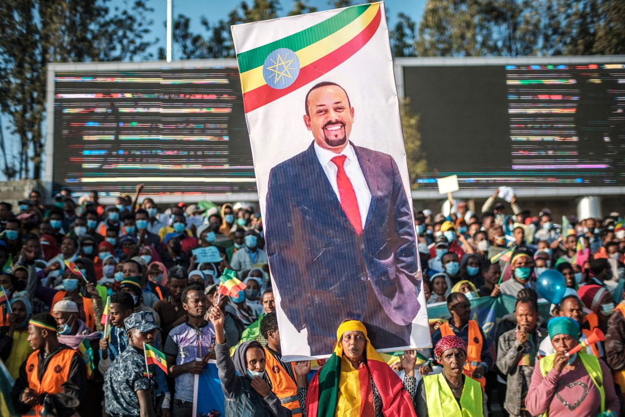 Een vrouw, gekleed in de kleuren van de Ethiopische vlag, houdt een banner omhoog met de afbeelding van premier Ahmed.