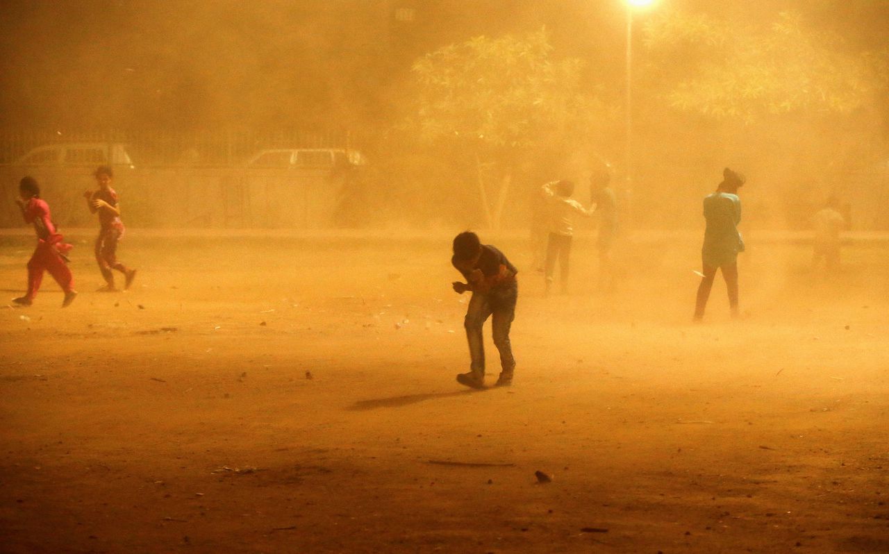Kinderen vecht zich door een zandstorm in New Delhi zondag.