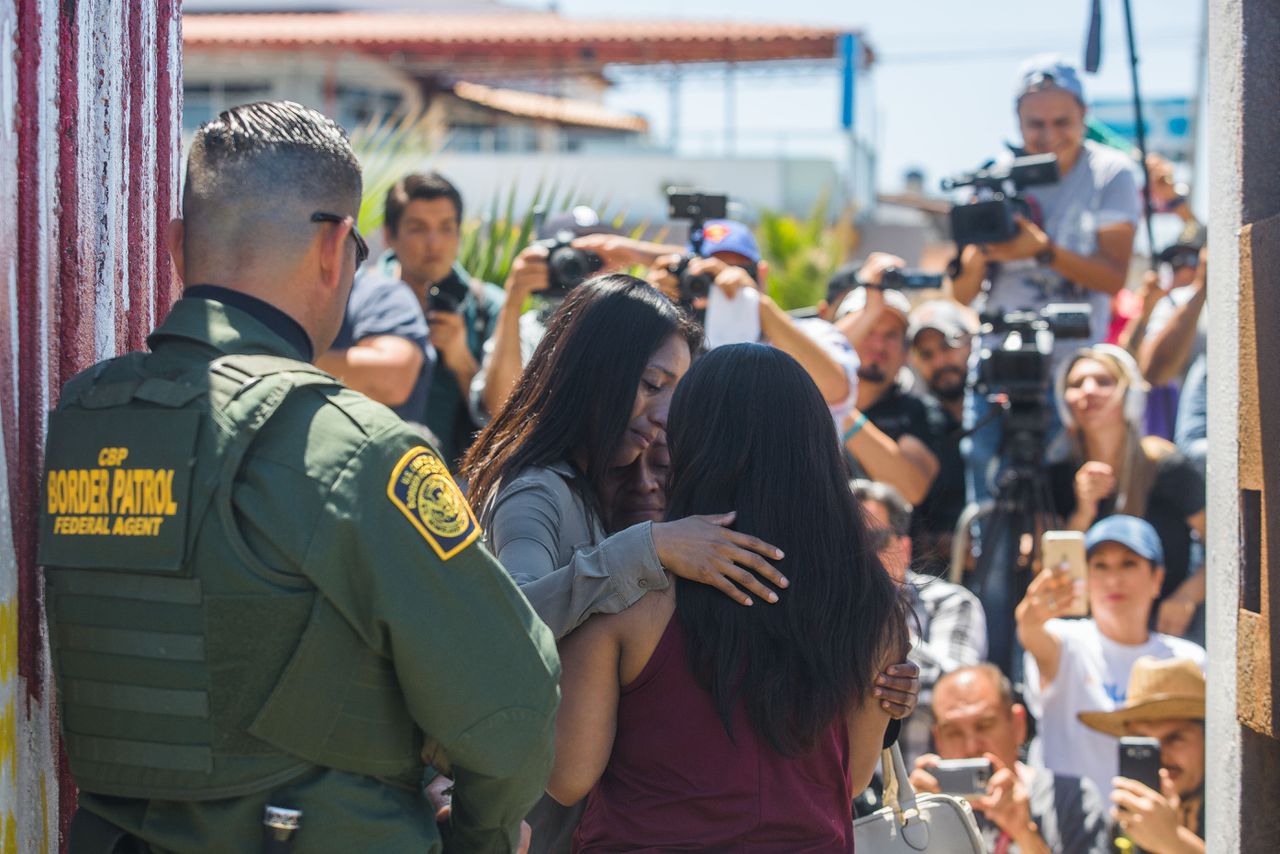 Jannet Lorenzo en haar zus Joselyn omhelzen hun moeder Reyna in het Vriendschapspark, op de grens tussen Mexico en de VS.
