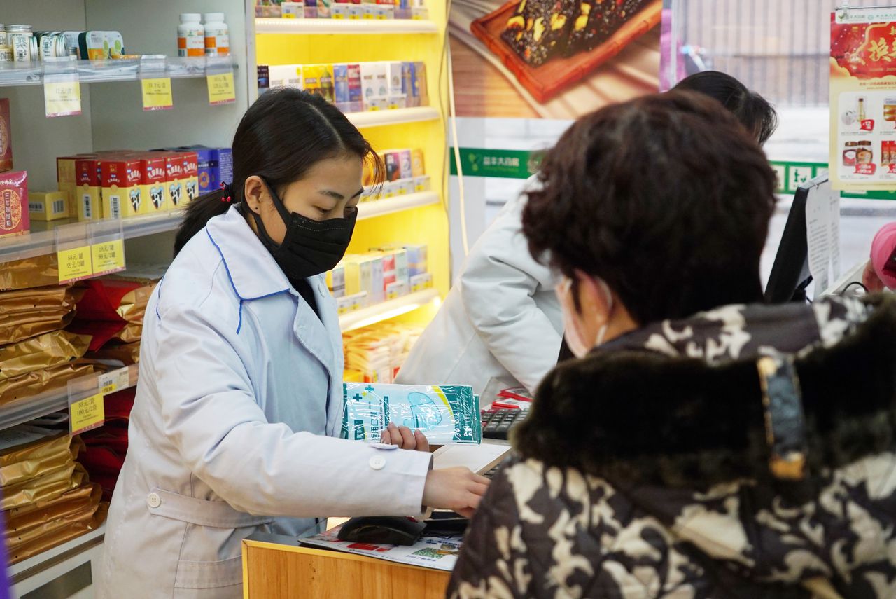 Personeel in de Chinese stad Wuhan verkoopt mondkapjes.