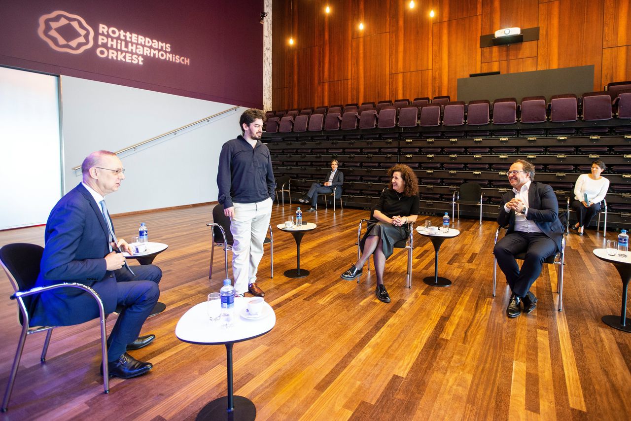 Chefdirigent Lahav Shani (staand) bij een werkbezoek van minister Ingrid van Engelshoven (Onderwijs, Cultuur en Wetenschap, midden) en Wouter Koolmees (Sociale Zaken, rechts) aan het Rotterdams Philharmonisch Orkest.
